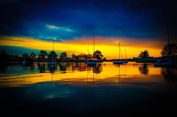 Piękny zachód słońca nad jeziorem z wieloma statkami i drzewami stojącymi obok siebie — Zdjęcie stockowe