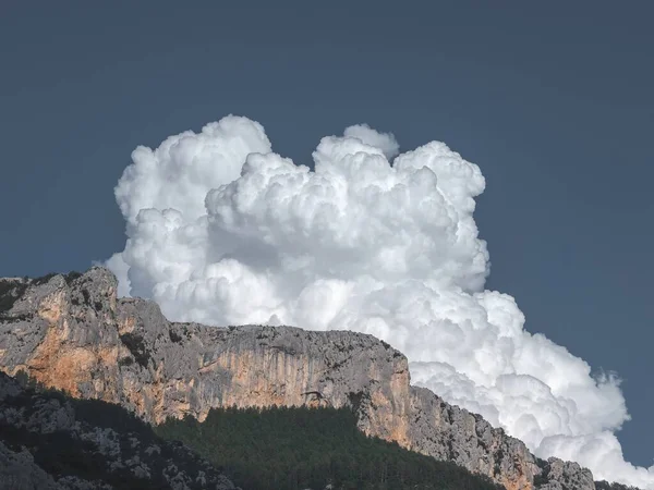 Belo tiro de um penhasco com uma nuvem em um céu azul no fundo — Fotografia de Stock