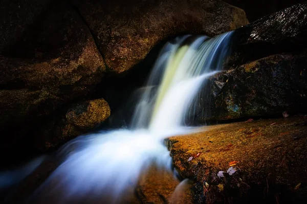 Cachoeira castanha escura no meio de uma floresta escondida com pedras de vidro gravadas em grandes tijolos — Fotografia de Stock