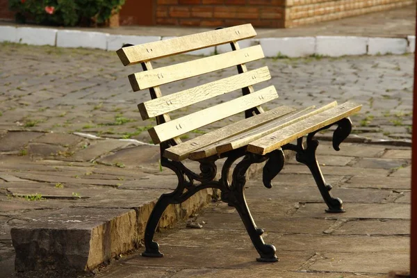 Ranní scéna hnědé dřevěné lavičky stojící v parku — Stock fotografie
