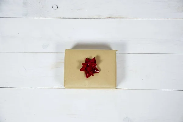 Εναέρια λήψη δώρου με κόκκινο φιόγκο σε λευκή ξύλινη επιφάνεια — Φωτογραφία Αρχείου