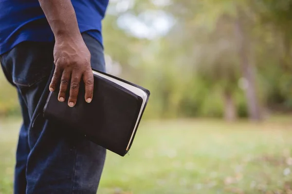 Primer plano de un macho sosteniendo la Biblia con un fondo borroso —  Fotos de Stock