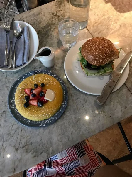 Tiro de ângulo alto vertical de uma panqueca inchada e um hambúrguer de café da manhã — Fotografia de Stock