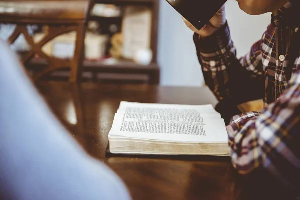Nahaufnahme eines Mannes, der ein Buch liest, während er Kaffee mit verschwommenem Hintergrund trinkt — Stockfoto