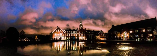 Vista mozzafiato di bellissimi edifici con luci riflesse nell'acqua sotto il cielo colorato — Foto Stock