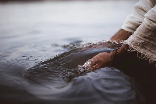 Cerrado disparo de una persona que lleva una túnica bíblica mientras se lava las manos en el agua. —  Fotos de Stock