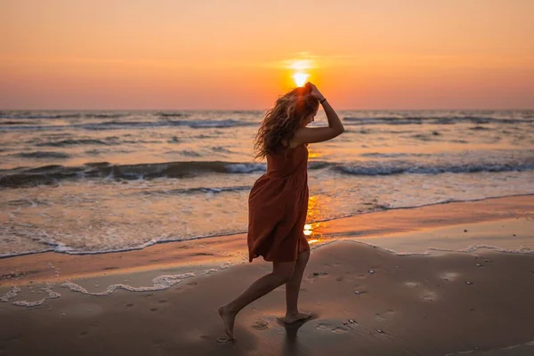 Hermoso tiro de un modelo disfrutando de la puesta de sol y tratando de seguir el sol en la playa. —  Fotos de Stock