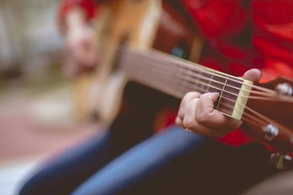 Closeup shot of a female playing the guitar with a blurred background — 스톡 사진