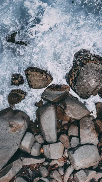 Tiro vertical de piedras grandes en el agua tormentosa del océano —  Fotos de Stock