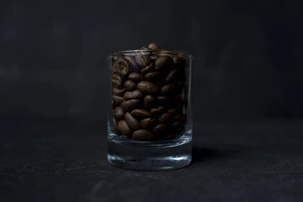 Tiro de close-up de um copo de grãos de café em uma superfície escura — Fotografia de Stock