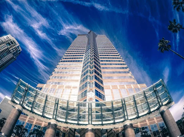 Niski kąt ujęcia pięknego bloku wieży z lustrzanymi oknami pod zapierającym dech w piersiach chmurnym niebem — Zdjęcie stockowe