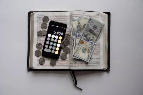 Fotografia aérea de um livro aberto com notas de dólar e um smartphone no topo — Fotografia de Stock