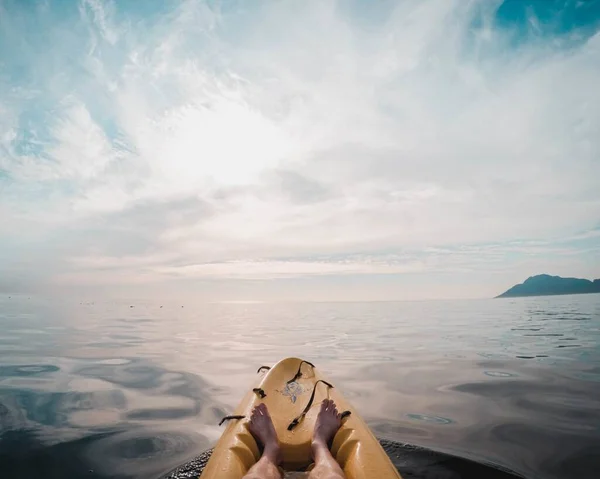 Hermosa foto de piernas humanas en un barco de surf amarillo en el centro del océano — Foto de Stock