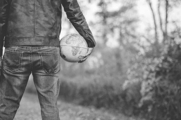 Black and white shot of a male holding the globe with a blurred background