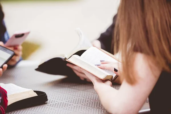 テーブルの周りに座って聖書を読んでいる女性のクローズアップショット — ストック写真