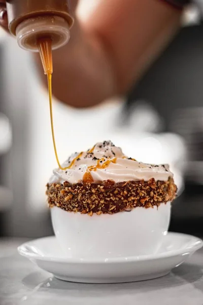 Vysoký úhel záběr barista dělat kávu s karamelovou omáčkou a šlehačkou v bílém šálku — Stock fotografie