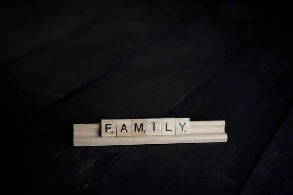 Primer plano de bloques de madera familia de ortografía con un fondo negro —  Fotos de Stock