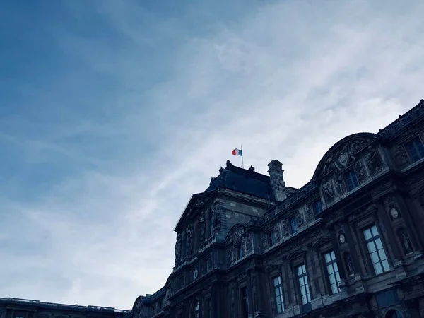Eine Betonburg mit der französischen Flagge darüber in Paris, Frankreich unter dem atemberaubenden wolkenverhangenen Himmel — Stockfoto