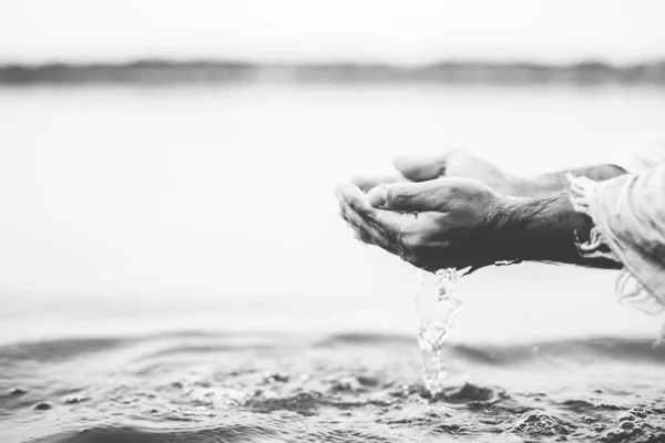 Primer plano de una persona vestida con una túnica bíblica sosteniendo agua con palmas en blanco y negro —  Fotos de Stock