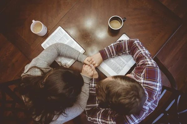 Overhead tiro de um casal de mãos dadas sobre a mesa perto de suas canecas de café — Fotografia de Stock