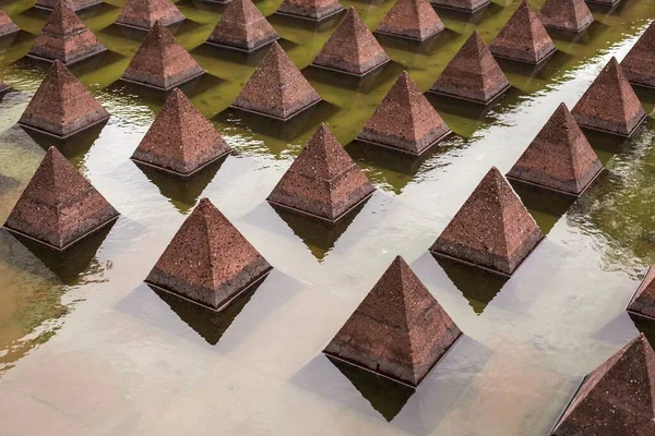 Shot of pink triangles symmetrically reflecting their silhouettes in a green lake — Stock Photo, Image