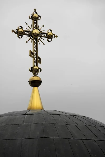 Primer plano vertical de una cruz dorada decorada en una cúpula de iglesia negra —  Fotos de Stock