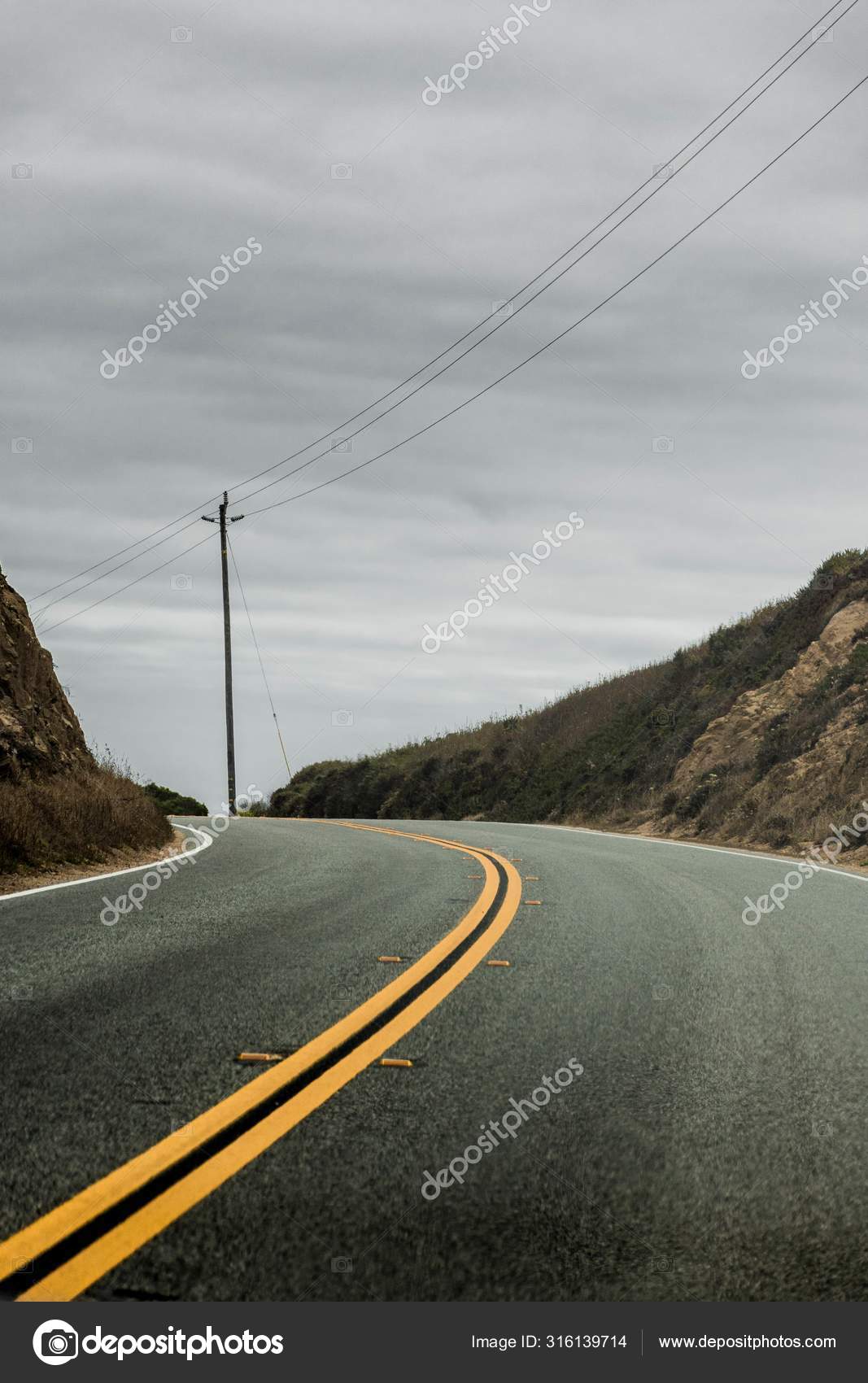 Vertikale Aufnahme Einer Beidseitigen Autobahn Die Von Hugeln Umgeben Ist Im Hintergrund Der Wolkenverhangene Graue Himmel Stockfoto C Wirestock