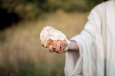 Closeup shot of Jesus Christ handing out bread with a blurred background clipart