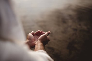 Beautiful shot of a male wearing a biblical robe holding water with his palms clipart