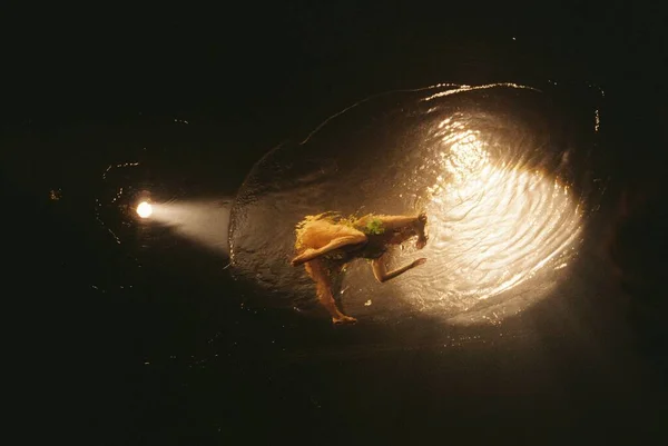 Bonito tiro de uma mulher nadando no oceano com um holofote iluminando-a — Fotografia de Stock