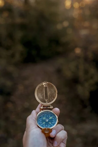 Ujęcie pionowe osoby trzymającej kompas z zamazanym tłem - zagubiona koncepcja — Zdjęcie stockowe