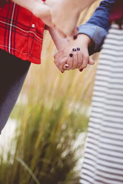 Closeup shot of females holding hands and praying with a blurred background — Stock Photo, Image