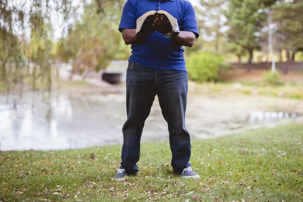 Мужчина, стоящий на травянистом поле во время чтения Библии с размытым фоном — стоковое фото