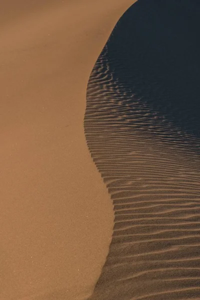 Captura vertical abstracta del agua que llega a la arena de la playa dejando senderos — Foto de Stock