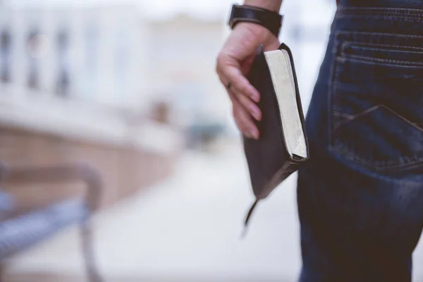 Primer plano de un macho sosteniendo la Biblia con un fondo borroso — Foto de Stock