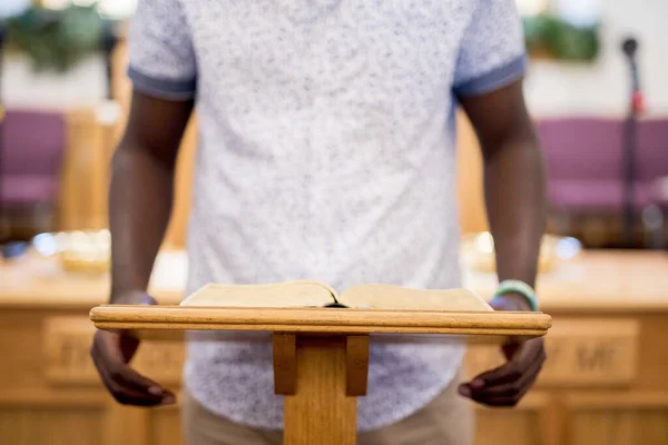 Κοντινό πλάνο ενός ατόμου που διαβάζει τη Βίβλο σε μια ξύλινη βάση στην εκκλησία — Φωτογραφία Αρχείου