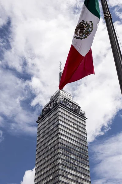 Tiro vertical de la bandera de México ondeando sobre un edificio de gran altura — Foto de Stock