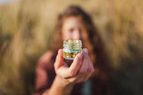 Selektive Fokusaufnahme eines Modells mit einem Glas voll goldenem Glanz — Stockfoto