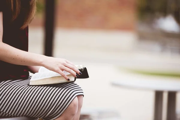 Close-up shot van een vrouw zitten tijdens het lezen van de bijbel met een wazige achtergrond — Stockfoto