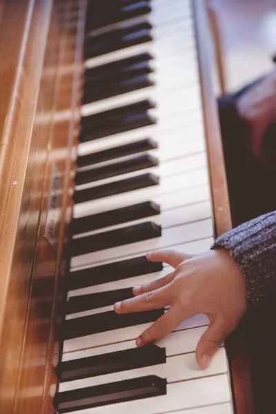 背景がぼやけてピアノを弾く子供の垂直ショット — ストック写真