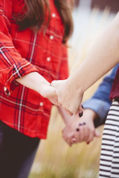 Vertikale Nahaufnahme von Frauen, die Händchen halten, während sie vor verschwommenem Hintergrund beten — Stockfoto