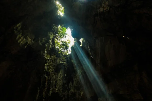 Impresionante paisaje de rayos de sol brillantes cayendo dentro de una cueva que ilumina los alrededores —  Fotos de Stock