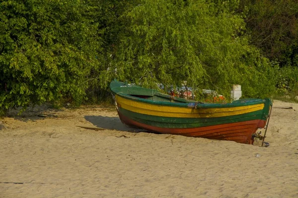 Prachtige opname van een kleurrijke rubberboot aan de zandkust onder de hellende bomen — Stockfoto
