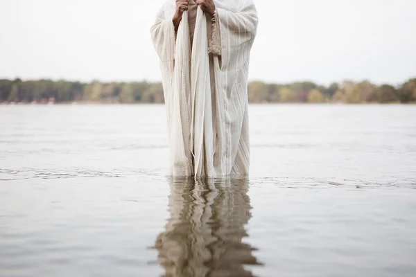 Personne portant une robe biblique debout dans l'eau avec un fond flou — Photo