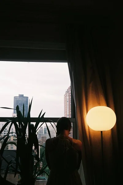 Вертикальный Снимок Одинокой Женщины Опущенной Головой Возле Балкона Рядом Лампой — стоковое фото