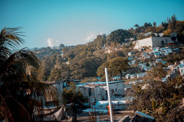 Hermosa toma de casas de pueblo en las colinas rodeadas de árboles bajo un cielo azul — Foto de Stock