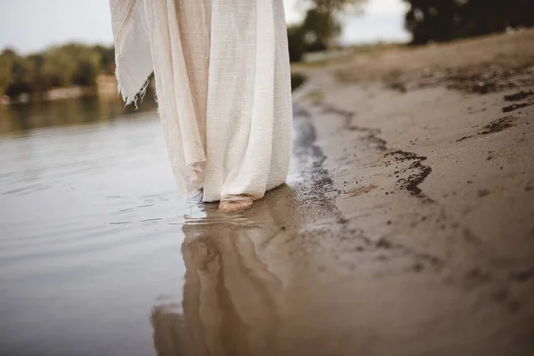 Gros plan d'une personne portant une robe biblique marchant sur le rivage avec un fond flou — Photo