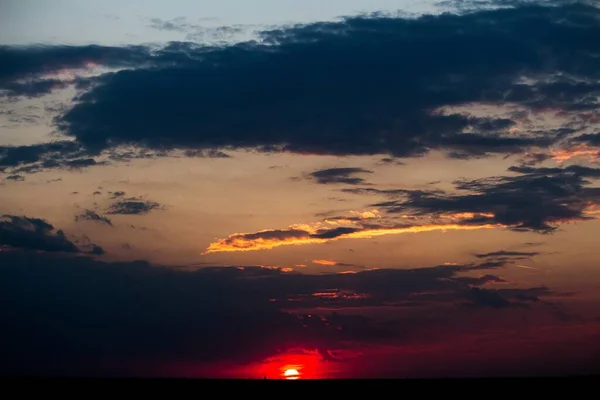 Mooie zonsondergang ziet eruit alsof de zon op het punt staat in de zee te duiken onder de bewolkte hemel — Stockfoto