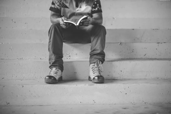 Pessoa sentada nas escadas enquanto lê a Bíblia em preto e branco — Fotografia de Stock