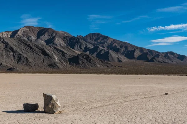 Escena del desierto con un largo rastro dejado por dos piedras en el suelo seco y colinas en la parte posterior —  Fotos de Stock